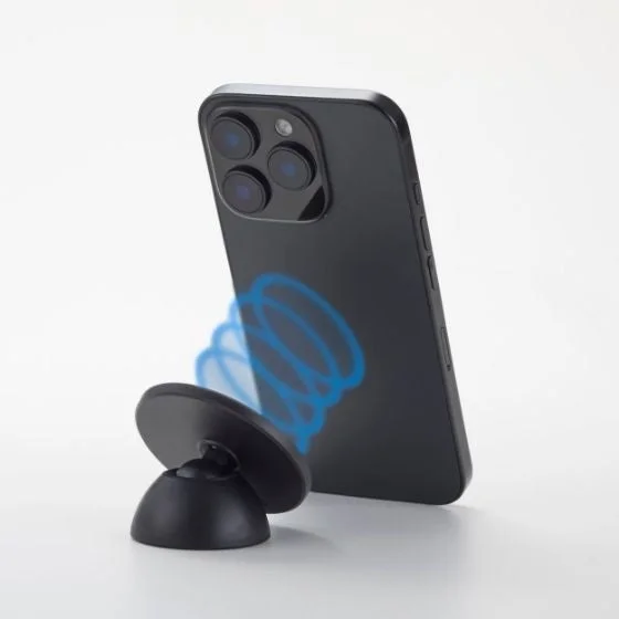 黒いスマートフォンが、黒いマグネット式のスマホスタンドに立てかけられている様子です。スマートフォン背面には青い磁力の渦巻きが描かれ、安定した装着状態を示しています。