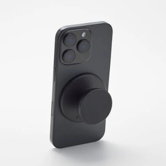 黒いiPhoneの背面に、黒いマグネット式スマートフォン用グリップアクセサリーが取り付けられている写真です。シンプルな白い背景で、製品の機能性とデザインが際立っています。