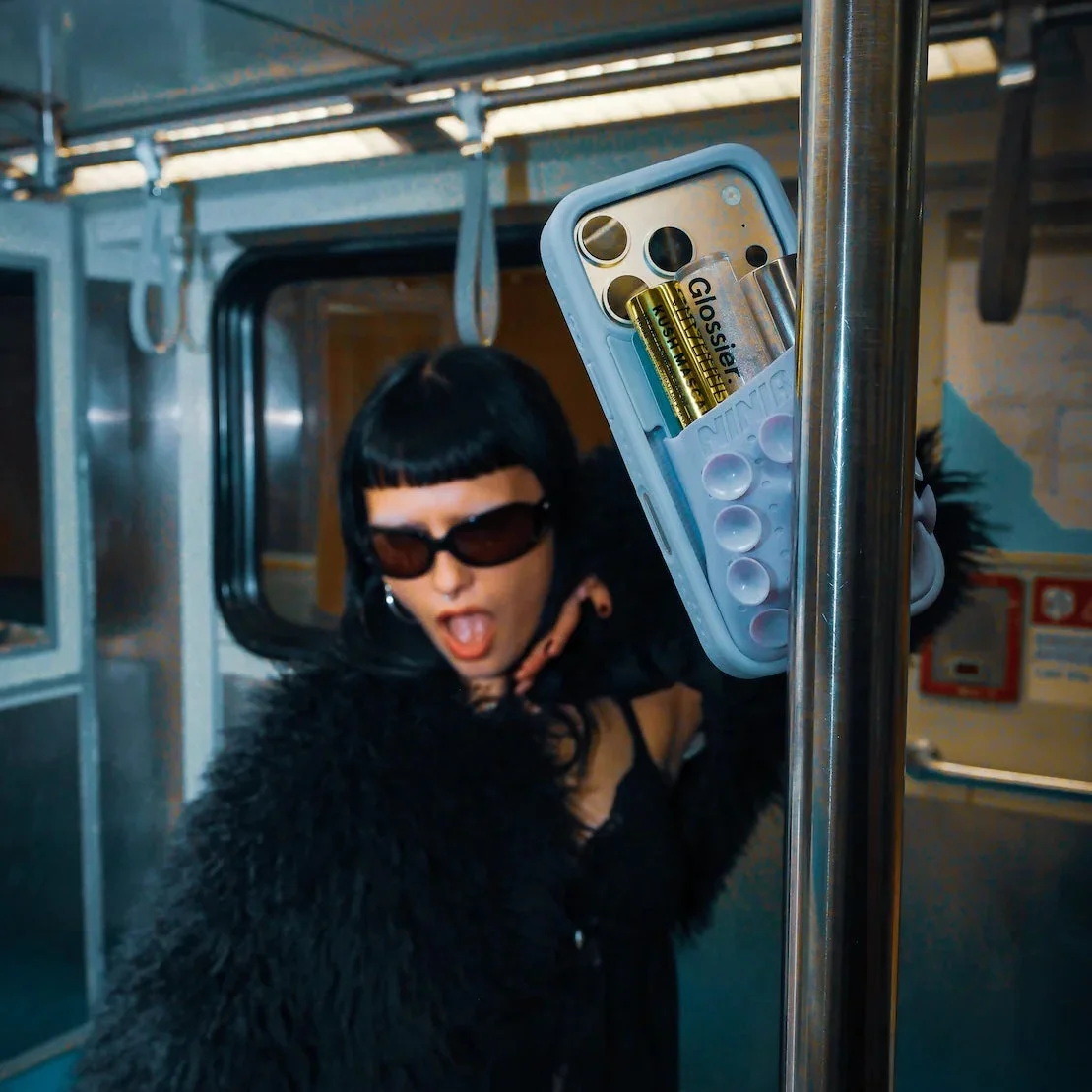 地下鉄の車内で、スマホケースを見せる女性。