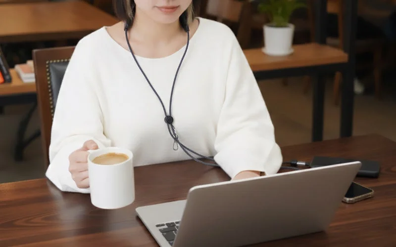 カフェでノートパソコン作業中にスマホショルダーを着用している女性